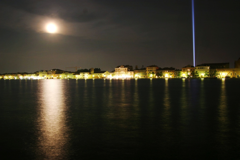 Cleave 03 (Transmission: Visions of the Sleeping Poet), Cerith Wyn Evans, 2003. Image: Polly Braden, © the artist. Venice by night with a blue light beam on the right hand side and the moon on the left